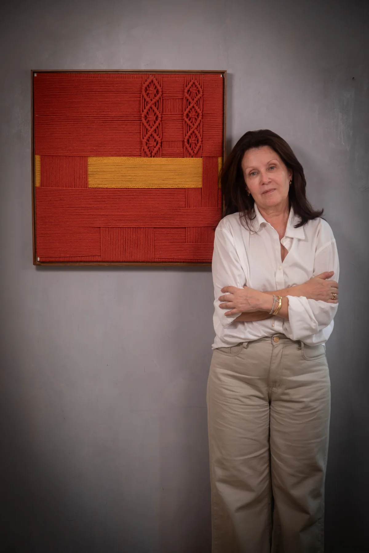 The Estudio Corda artist beside her finished red and yellow textile artwork