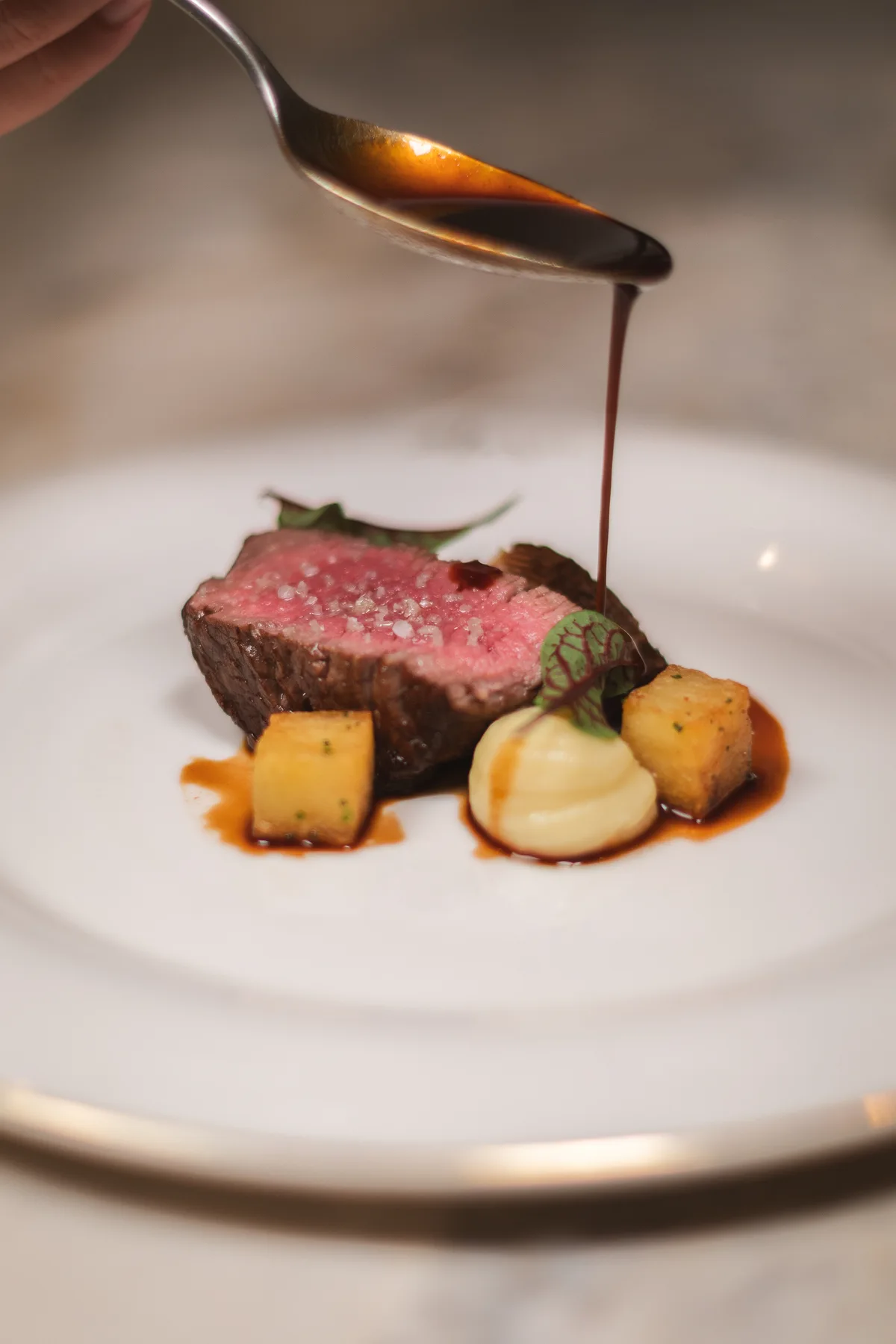 Sauce poured over a plated steak at Marie Cuisine Jardins
